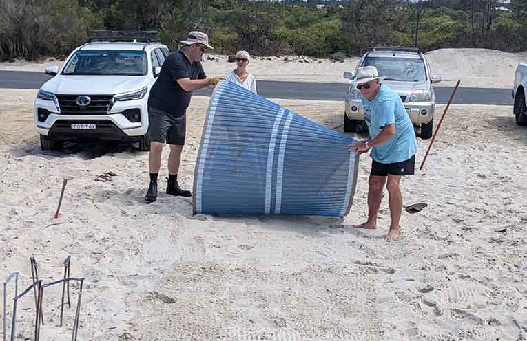 HNTGPA Vice President Thomas, President Sandra, and Secretary Bruce manually re-rolling the MobiMats at Jimmys Beach. Photo: Sherrie O’Keefe.