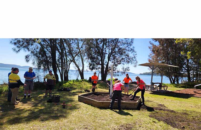 Tilligerry Lions and Hunter River High students work together to build the Peace Garden. Photo: Supplied.